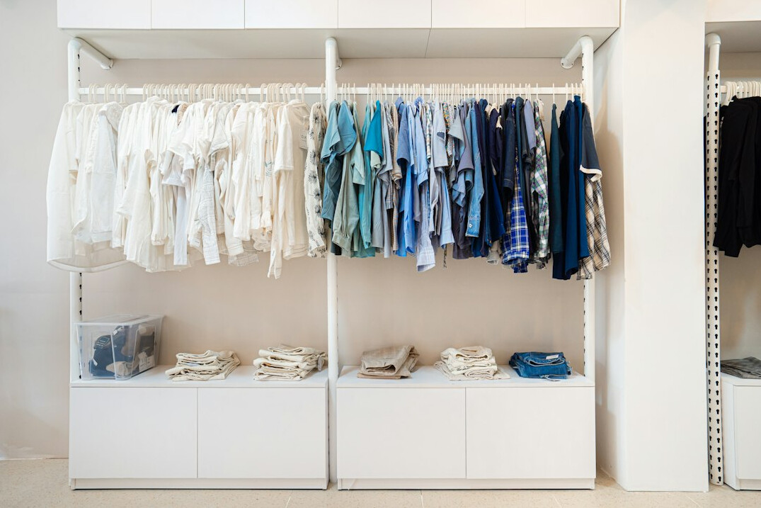 Wardrobe with clothes hanging on a rail sorted by colour